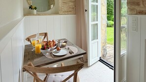 Ein Frühstückstisch mit Croissants, Eiern und Obst, einer Orangensaftflasche und einer Schale Erdbeeren.