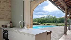 Una cocina moderna con una isla grande, horno empotrado y vistas a una piscina.