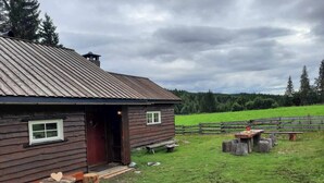 A rustic wooden cabin with a metal roof, a wooden deck, and a bench. - Cottage in the Forest (Lillehammer)