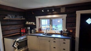 A compact kitchen with a built-in oven, a sink, and a window. - Cottage in the Forest (Lillehammer)
