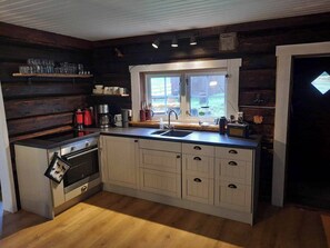 A compact kitchen with a built-in oven, a sink, and a window. - Cottage in the Forest (Lillehammer)