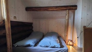 A small, cozy room with a wooden bunk bed and a single bedside table with a lamp. - Cottage in the Forest (Lillehammer)