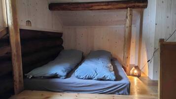 Ein kleiner, gemütlicher Raum mit einem Holzbett und einem Nachttisch mit Lampe.