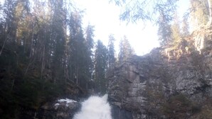 A waterfall cascading down a rocky cliff surrounded by trees. - Cottage in the Forest (Lillehammer)