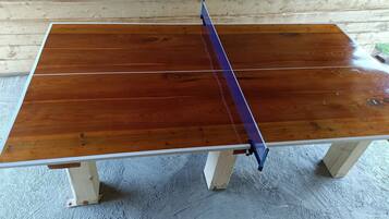 Une table en bois surmontée d’un filet bleu, placée contre un mur en bois.
