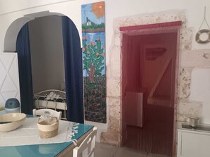 Ein Zimmer mit einem Bett, einem Tisch mit Korb und Schüssel, einem Bild und einer roten Tür.
