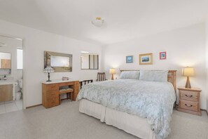 A bedroom with a bed, bedside tables, a desk, and a mirror. - Ocean House, by Vinifera Homes (Gualala)