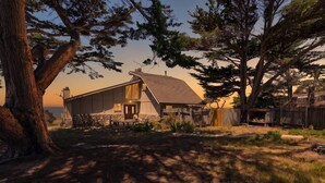 Una casa con tetto spiovente, fondamenta in pietra e recinzione in legno.