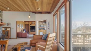 Un'ampia zona giorno con un'ampia finestra, un soffitto in legno e un'accogliente area salotto.