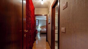 A hotel hallway with a wooden door, a red curtain, and a bed visible in the background. - Grand Canal Palazzo Retreat with Private Canal Views in San Marco (Venezia)