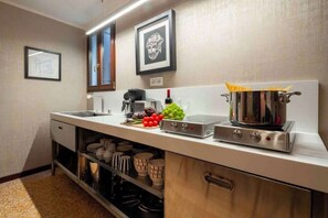 Una cocina con estufa de acero inoxidable, una cafetera y una olla de espagueti.