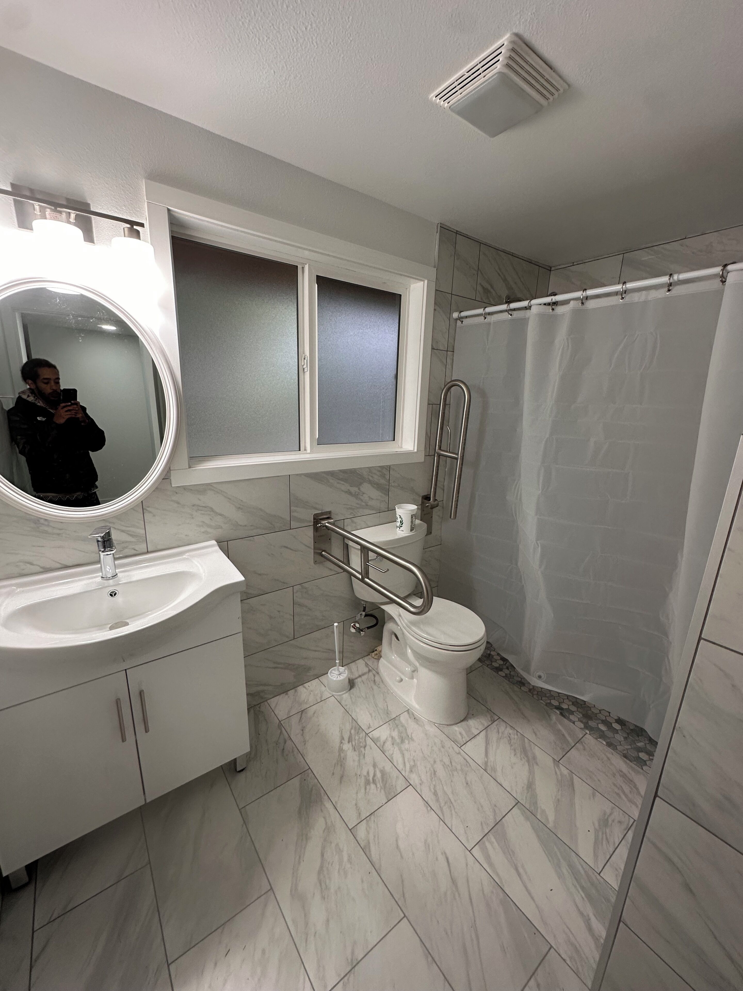 Ein Badezimmer mit weißem Waschbecken, Spiegel, Toilette und Duschvorhang.