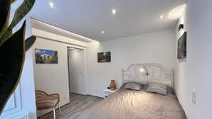 A bedroom with a bed, a chair, a nightstand, and wall-mounted lights.
