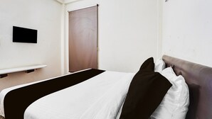 Een hotelkamer met een bed, een flatscreen televisie, een deur en een wandplank.