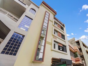 Ein mehrstöckiges Hotel mit einer auffälligen vertikalen Fensterreihe, einem Balkon im zweiten Stock und einem Schild, das es als Hotel kennzeichnet.