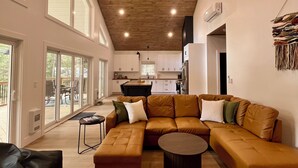 A modern living room with a sectional sofa, a coffee table, and a dining area with a kitchen in the background.