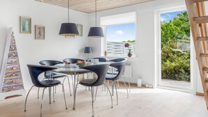 A modern dining area with a round table, black chairs, and pendant lights. - "Lotte" - 1.5km from the sea by Interhome (Skagen)