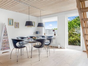 A modern dining area with a round table, black chairs, and pendant lights. - "Lotte" - 1.5km from the sea by Interhome (Skagen)