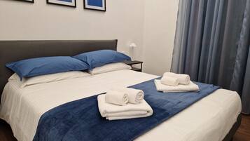 Ein Hotelzimmer mit einem Doppelbett, zwei Kissen, einem Nachttisch, einer Lampe und zwei Handtüchern.