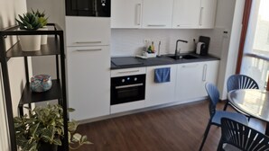 Et moderne køkken med hvide skabe, en sort bordplade og et spiseområde med et bord og stole.