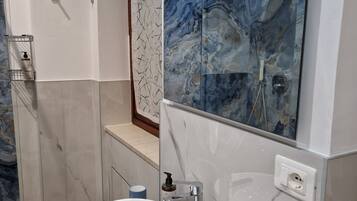 A bathroom with a white sink, a mirror, and a marble backsplash.