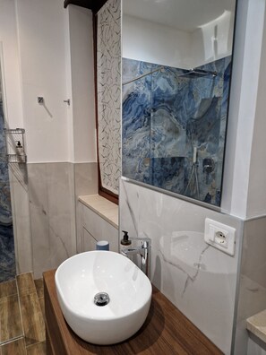 A bathroom with a white sink, a mirror, and a marble backsplash. - Beki's Apartment – In the heart of Alba, Piazza Garibaldi (Alba)