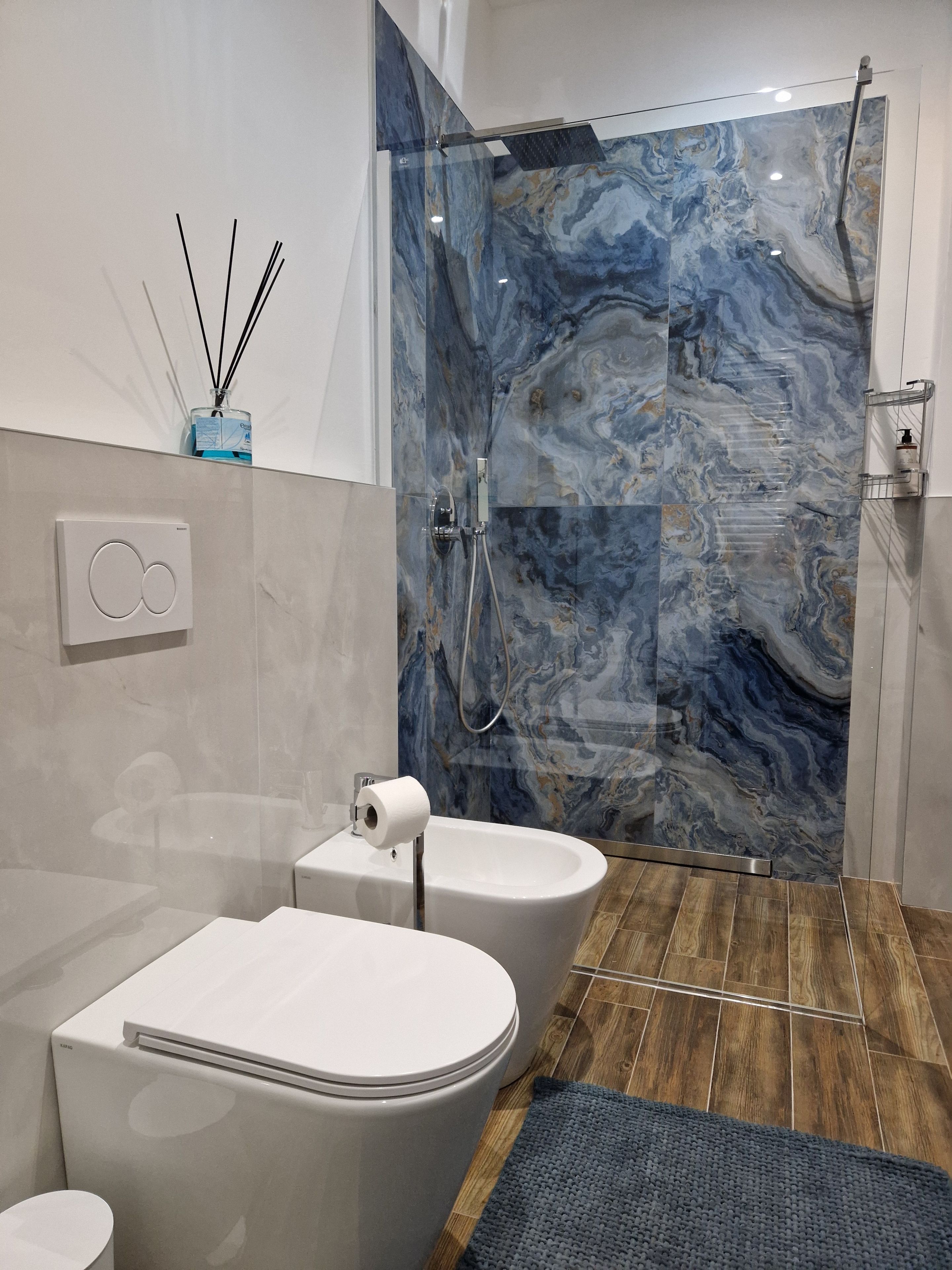 Un bagno moderno con parete doccia in marmo, un water e un bidet.