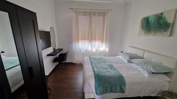Ein Hotelzimmer mit einem Bett, einem Schreibtisch, einem Stuhl, einem Kleiderschrank und einem fenster mit Vorhängen.