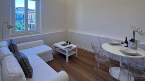 Ein modernes Wohnzimmer mit einem weißen Sofa, einem Couchtisch, einem Esstisch mit Stühlen und einem Fenster mit Blick.