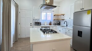 A modern kitchen with a central island, stainless steel appliances, and a herringbone-patterned floor. - Leleka's Cabin - E4 (Flowers Bay)