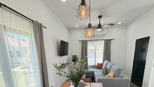 A dining area with a wooden table set for four, a vase with greenery, and pendant lighting. - Leleka's Cabin - E4 (Flowers Bay)
