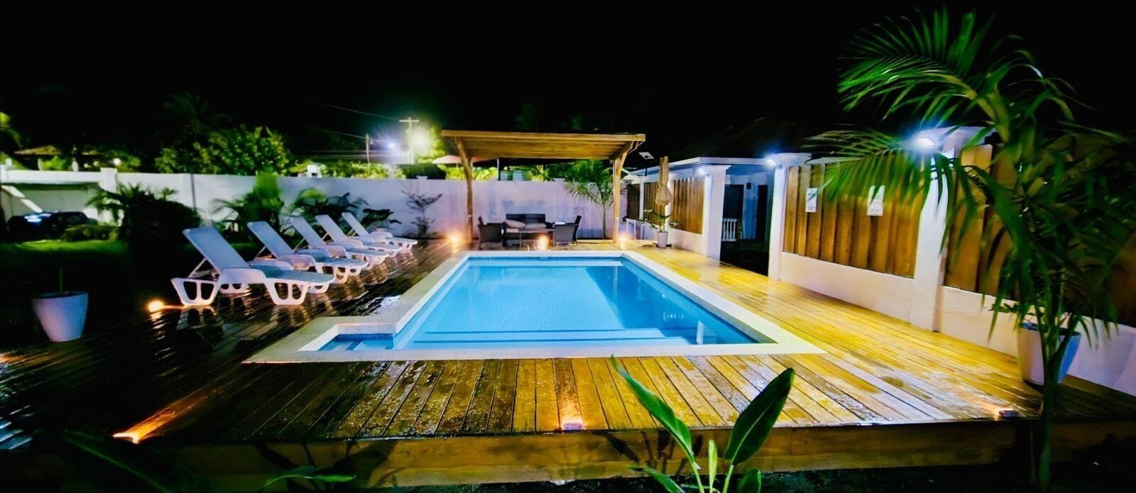 A swimming pool with lounge chairs and a covered seating area.