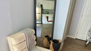 Ein Zimmer mit einem beigefarbenen Sofa, einem großen Spiegel, Korbwannen und einem Holzboden.