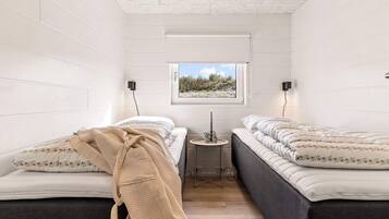 Ein Schlafzimmer mit zwei Betten, einem kleinen Tisch, einem Fenster mit Blick und einer Decke mit strukturierter Musterung.