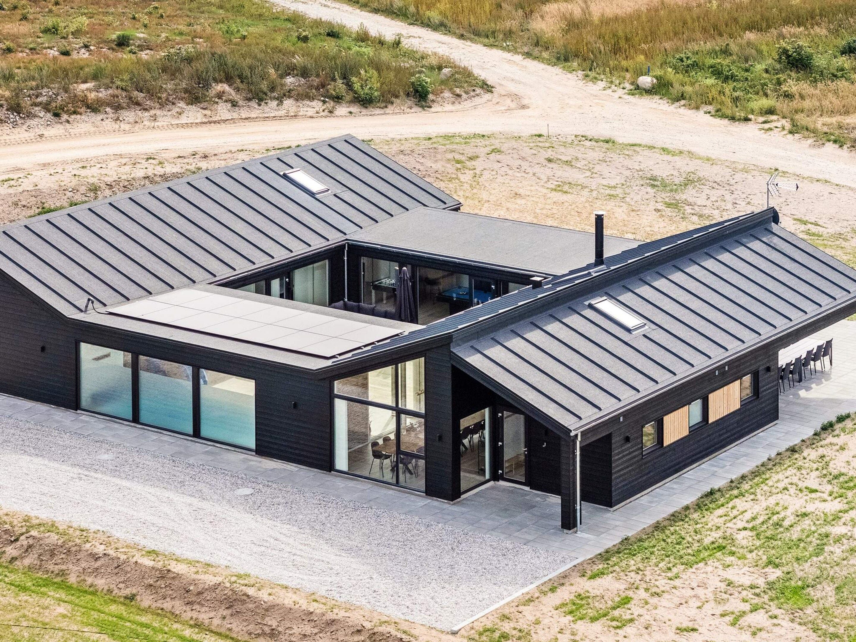 Et moderne hus med fladt tag, store glasvinduer og en grusbelagt indkørsel.
