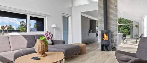 A modern living room with a fireplace, grey sofas, a coffee table, and a view of the outdoors.