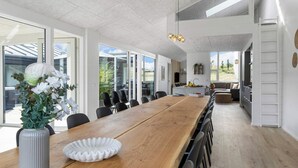 A modern kitchen with a large island, white cabinetry, and a view of the outdoors. - 5 Star Holiday Home in Glesborg (Glesborg)