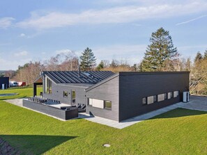 A modern building with a sloped roof, large windows, and a well-maintained lawn. - 5 Star Holiday Home in Glesborg (Glesborg)