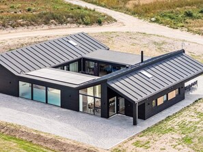 A modern house with a flat roof, large glass windows, and a gravel driveway. - 5 Star Holiday Home in Glesborg (Glesborg)
