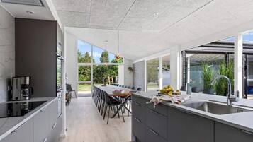 Eine moderne Küche mit Essbereich, großen Fenstern und Blick ins Freie.