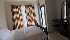 A bedroom with a bed, a ceiling fan, a window with curtains, a dresser, and a mirror. - Casa Eterna Primavera  (Playa del Carmen)