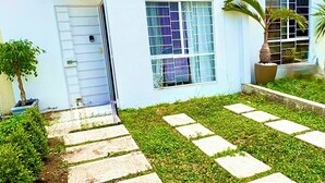 A modern building with a flat roof, large windows, and a small balcony. - Casa Eterna Primavera  (Playa del Carmen)