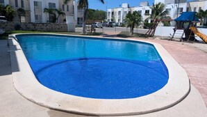 A swimming pool with a curved edge, surrounded by a concrete deck. - Casa Eterna Primavera  (Playa del Carmen)