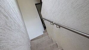 A staircase with beige tiles, a metal handrail, and a textured wall. - Casa Eterna Primavera  (Playa del Carmen)