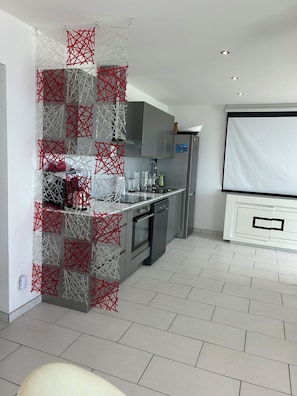 Eine moderne Küche mit Edelstahlgeräten, einem Einbauofen und einer grauen, gefliesten Spritzschutzwand.