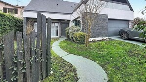 Une maison moderne avec un toit en pente, une allée pavée et une clôture en bois.
