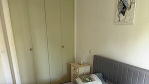 A bedroom with a bed, a nightstand, a wardrobe, and a wall decoration. - Charming two-bedroom apartment in La Motte-du-Couchant, 200 meters from the beaches (La Grande-Motte)