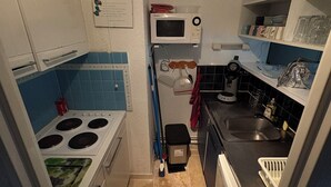 A compact kitchen with a stove, microwave, sink, and a small countertop area. - Charming two-bedroom apartment in La Motte-du-Couchant, 200 meters from the beaches (La Grande-Motte)