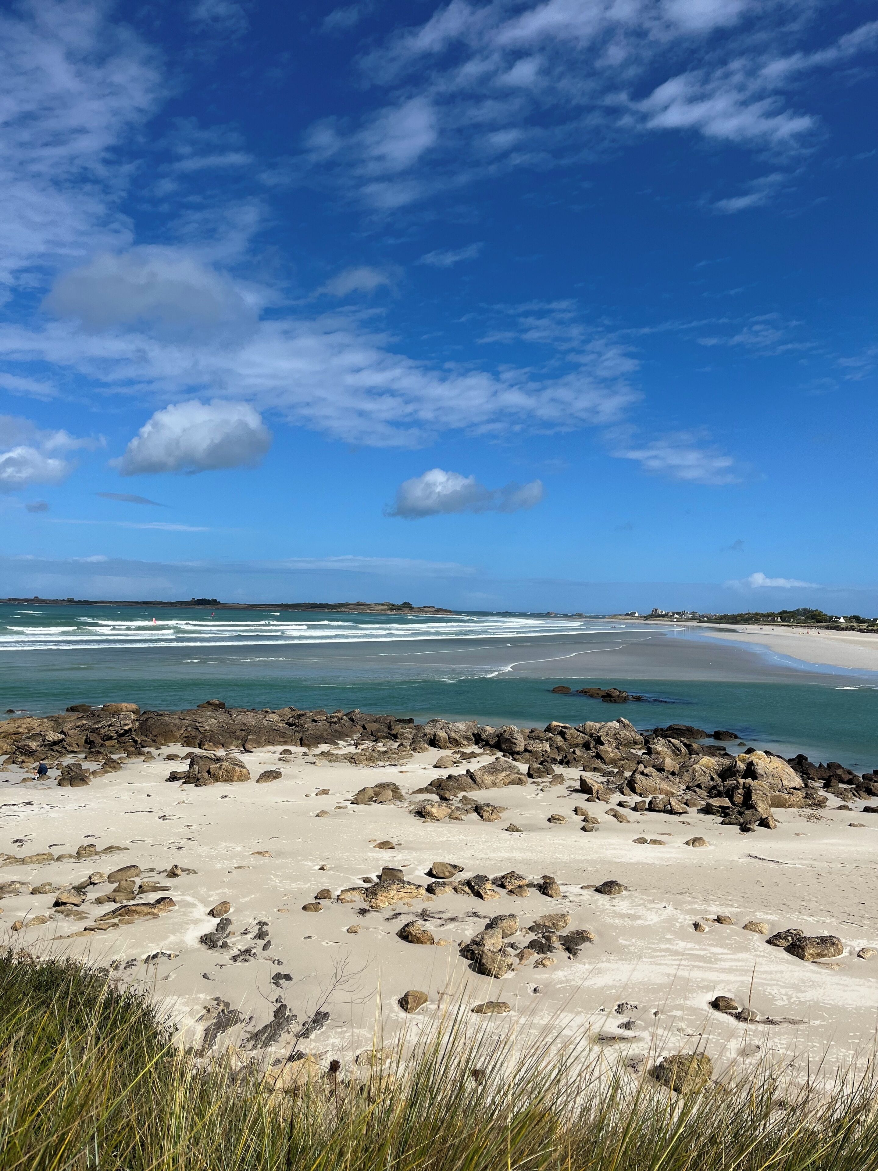 A beach with rocky foreground, ocean waves, and a clear sky.