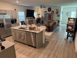 A modern kitchen with a central island, a dining area with a sofa, and a slot car track. - Super Clean new 1-Bd-1Bth N.Las Vegas, Aliante Casino, Golf, 15 min to Strip. (North Las Vegas)